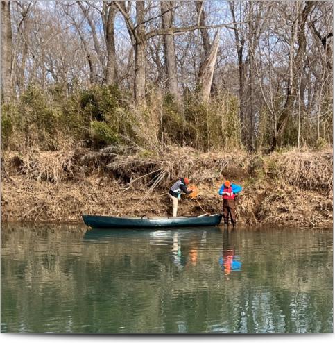 2 technicians on a canoe on the bank of the river